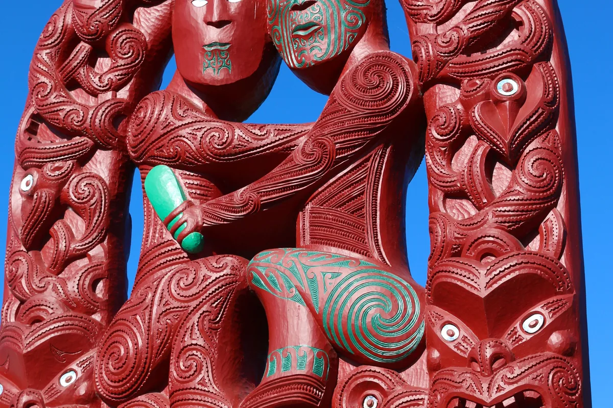 A detailed traditional Maori wood carving photographed in Rotorua against a blue sky